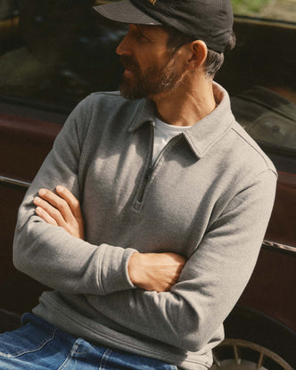 fit model leaning against a car wearing The Armor Quarter Zip in Heather Grey Cotton Hemp