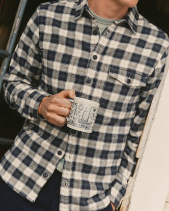 fit model leaning against the wall wearing The Crater Shirt in Woodland Plaid