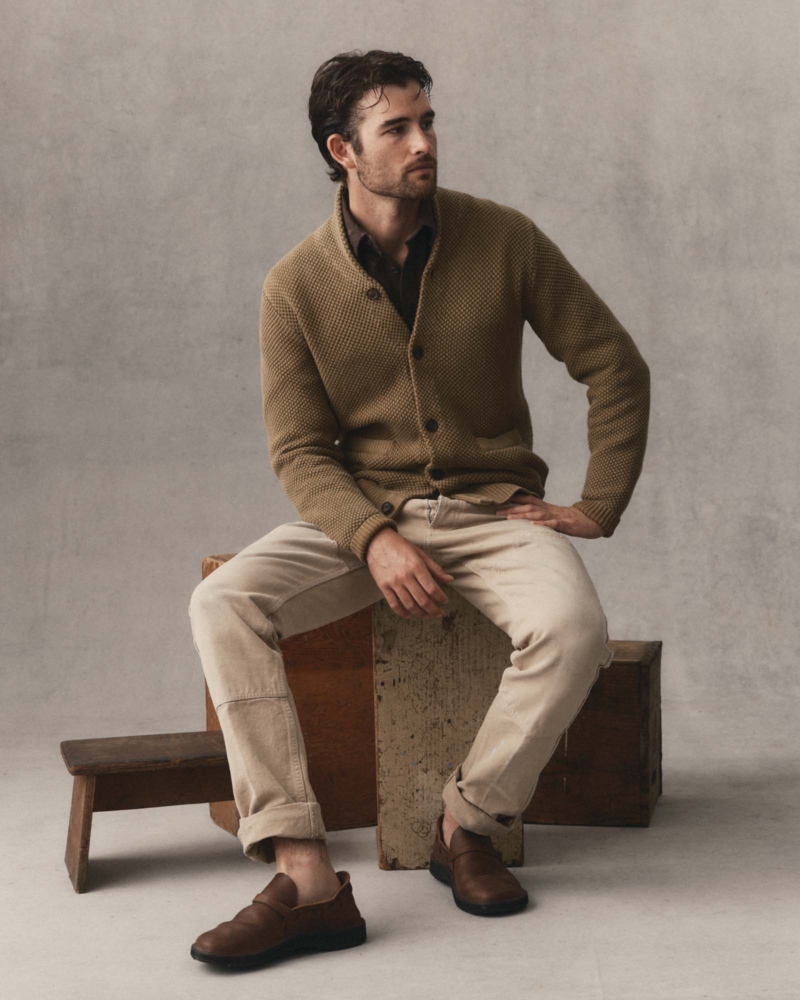 fit model sitting wearing The Crawford Sweater in Bay Leaf, Knits by Taylor Stitch