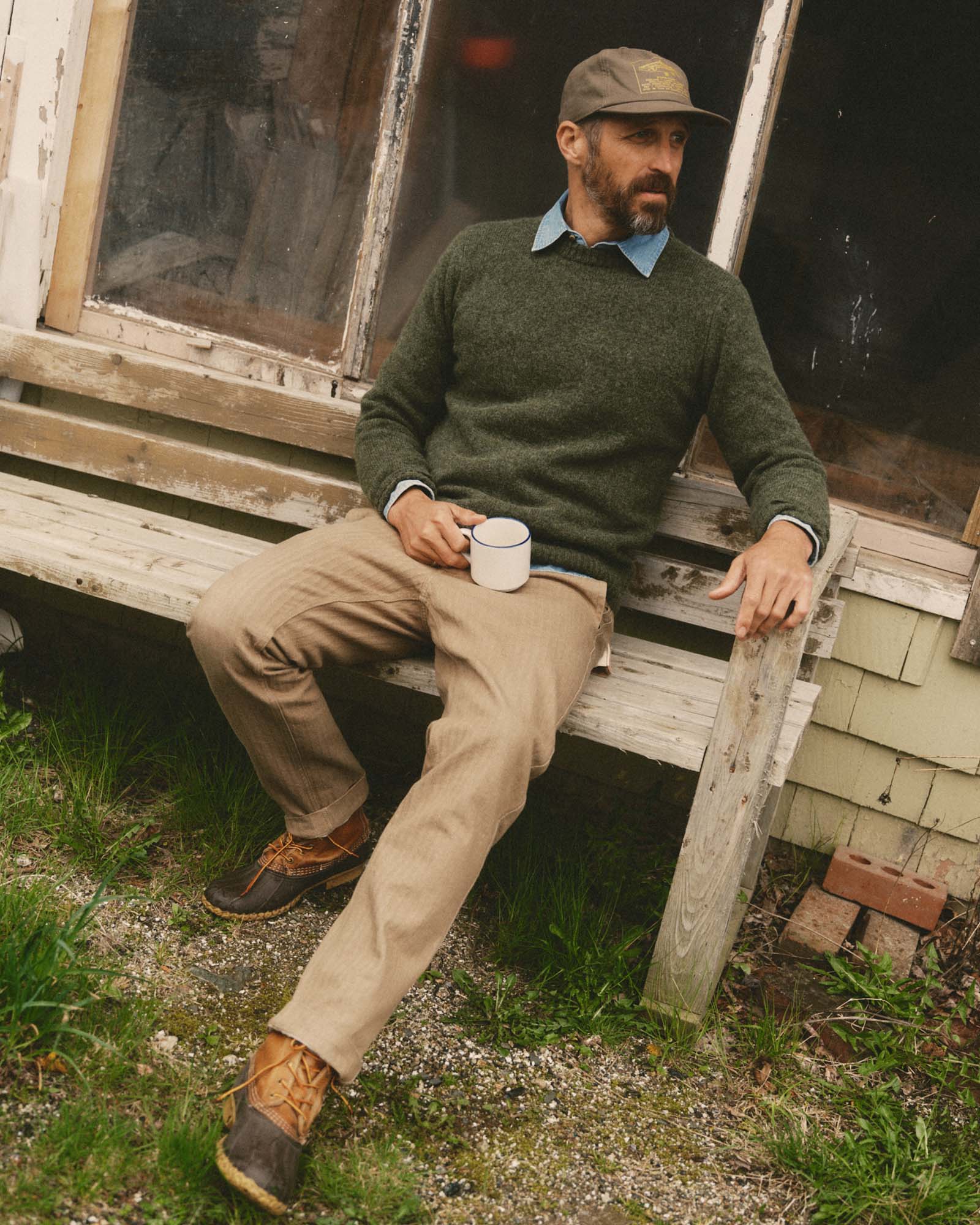 fit model sitting wearing The Emlen Pant in Khaki Herringbone, Bottoms by Taylor Stitch