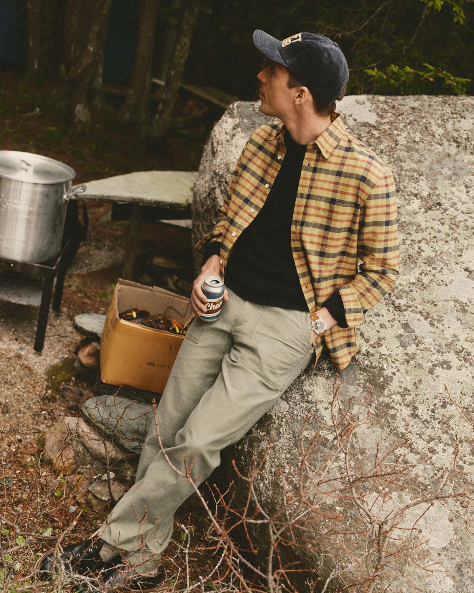 fit model leaning against a rock wearing The Jack in Marsh Check Oxford, Wovens by Taylor Stitch