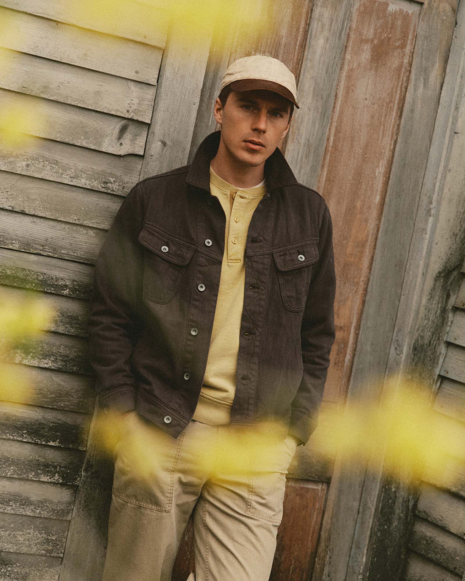 fit model leaning against the wall wearing The Long Haul Jacket in Soil Slub Denim, Outerwear by Taylor Stitch