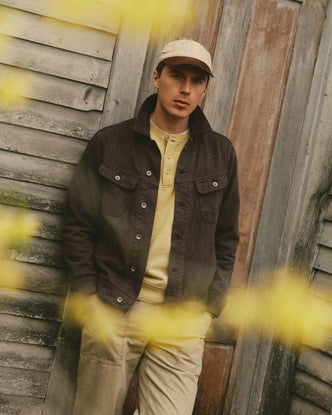 fit model leaning against the wall wearing The Long Haul Jacket in Soil Slub Denim