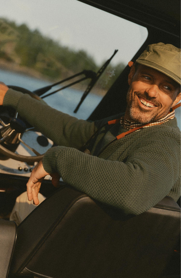 fit model sitting wearing The Crawford Crew Sweater in Fatigue Olive
