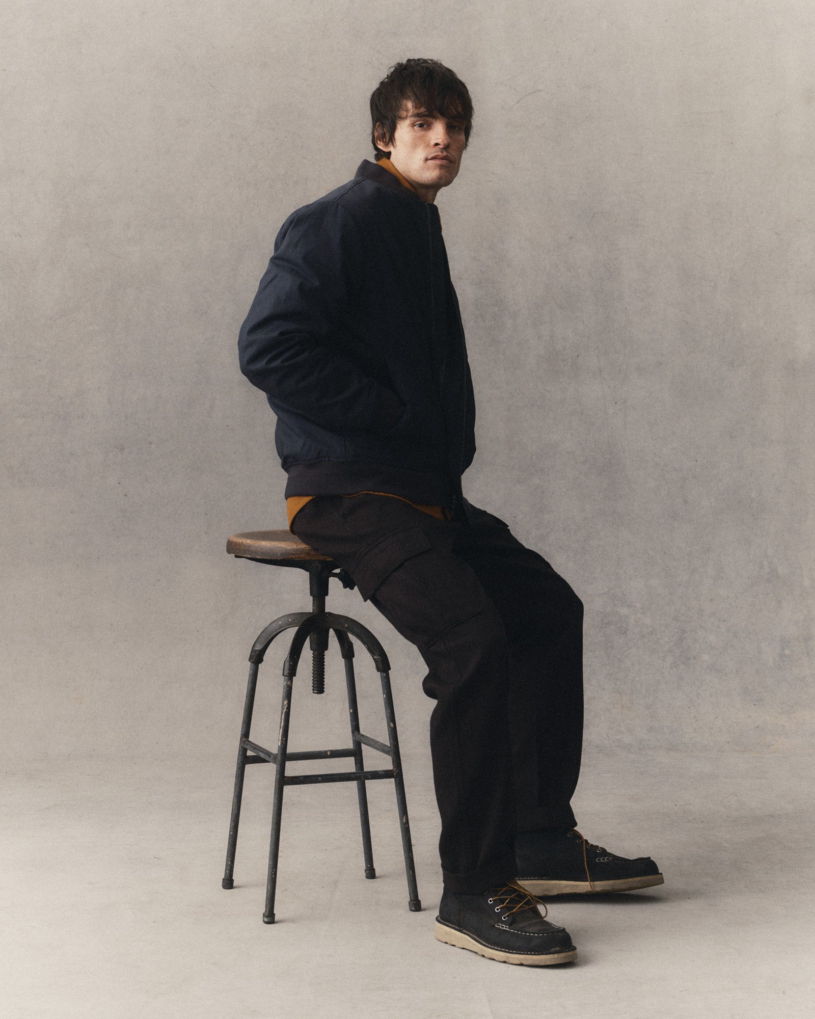 fit model sitting wearing The Forest Cargo Pant in Coal Broken Twill, Bottoms by Taylor Stitch