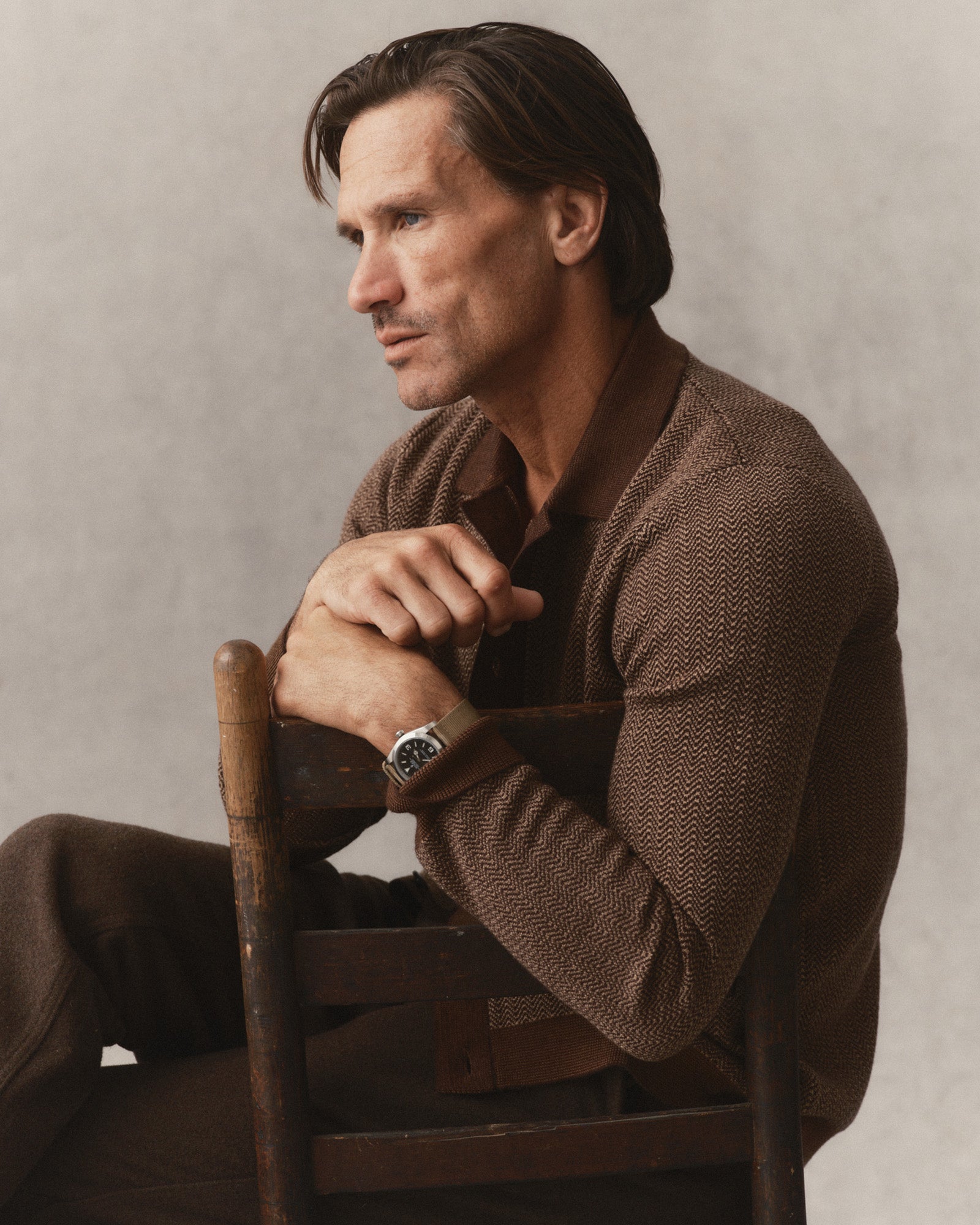fit model sitting on a chair wearing The Miles Sweater Polo in Espresso Merino, Sweaters by Taylor Stitch