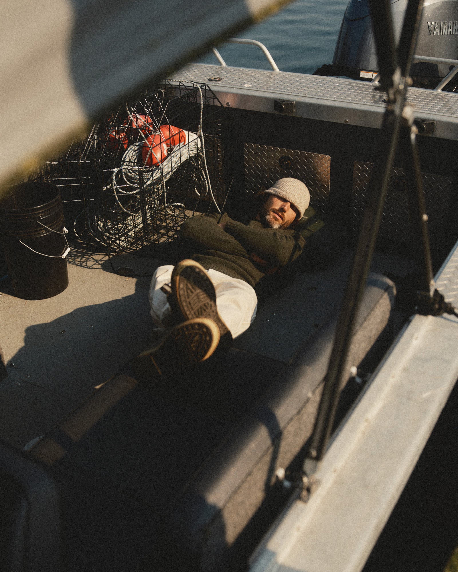 fit model lying on a boat wearing The Seafarer Rollneck Sweater in Olive Donegal, Sweaters by Taylor Stitch
