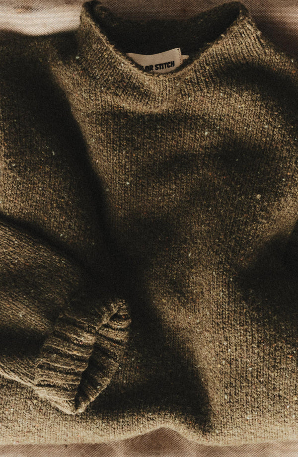editorial flatlay of The Seafarer Rollneck Sweater in Olive Donegal