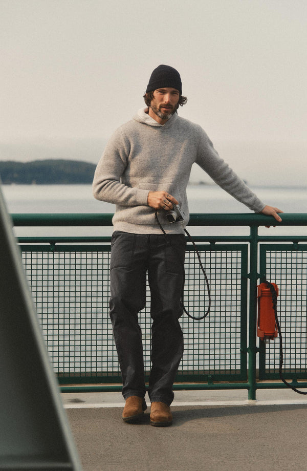 fit model leaning against a wall wearing The Breakwater Pant in Coal Ripstop