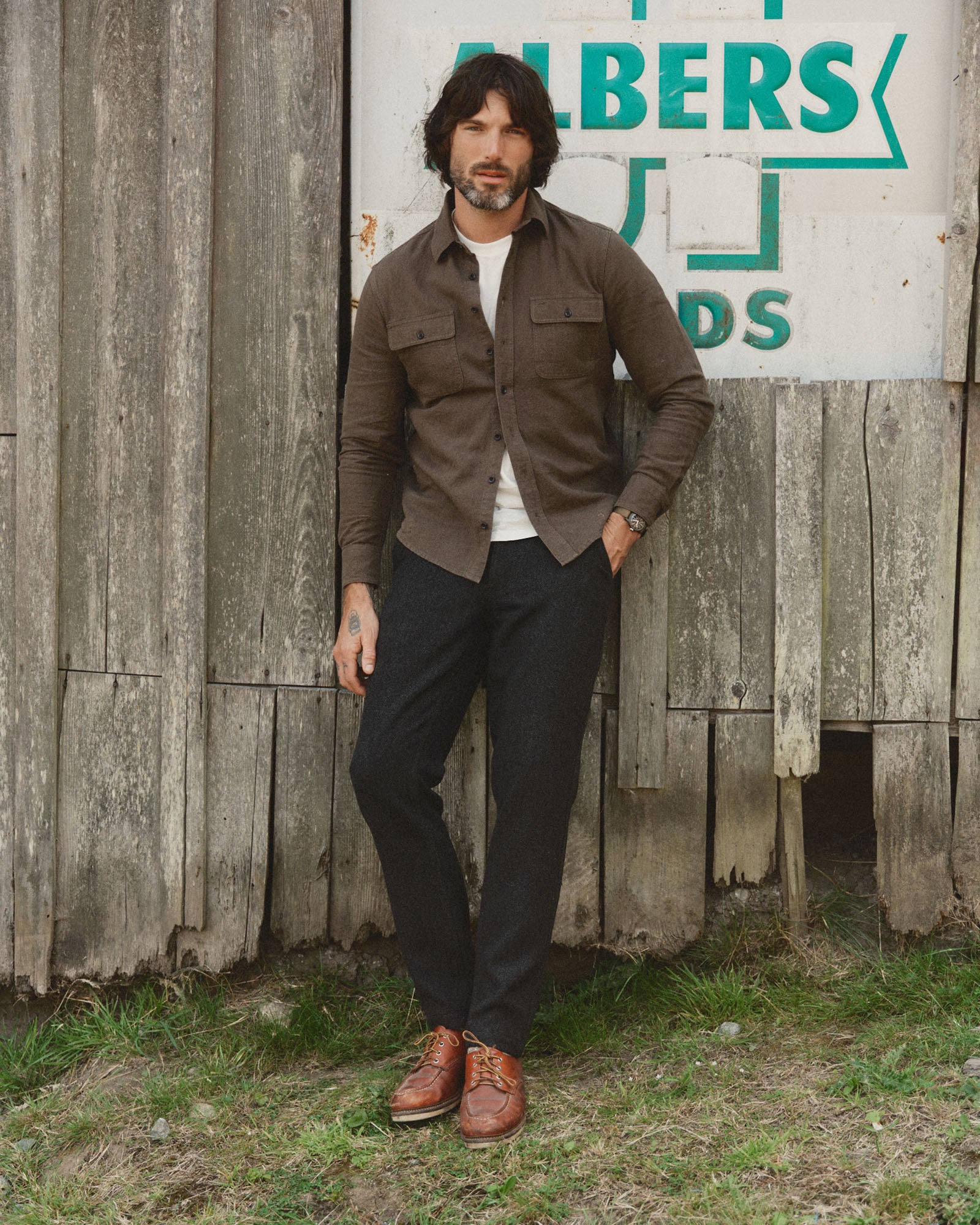fit model leaning against the wall wearing The Carnegie Pant in Coal Herringbone Wool, Bottoms by Taylor Stitch