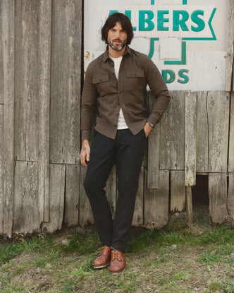 fit model leaning against the wall wearing The Carnegie Pant in Coal Herringbone Wool