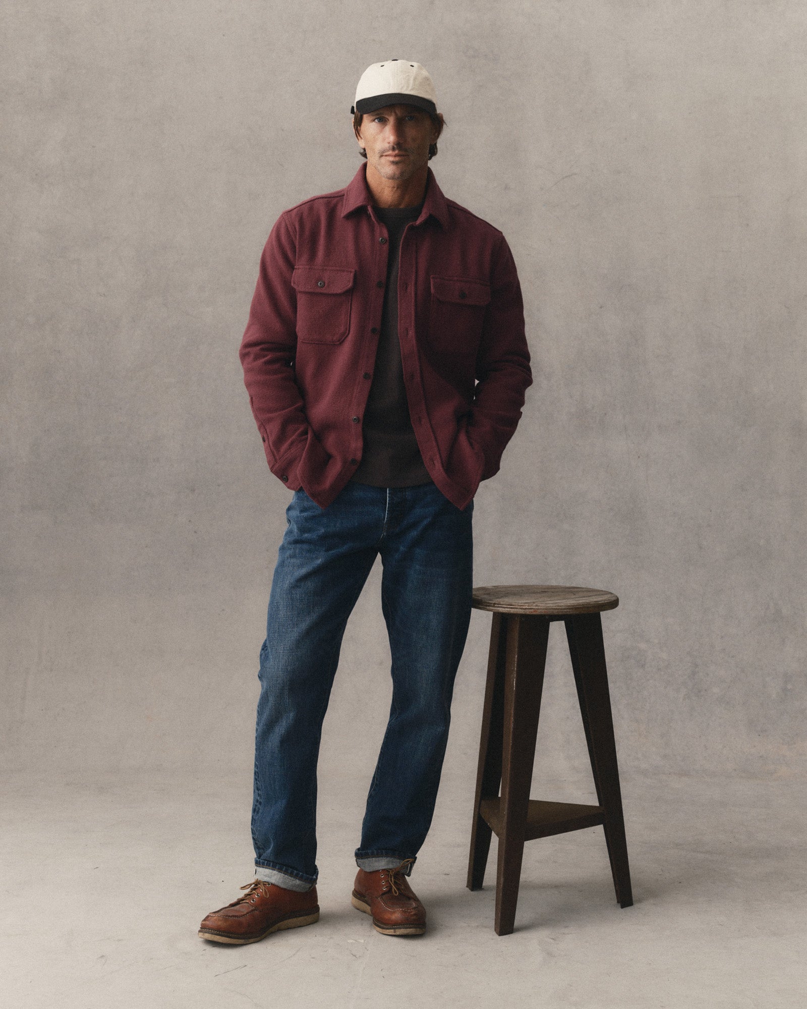 fit model posing next to a stool wearing The Division Shirt in Black Cherry, Wovens by Taylor Stitch