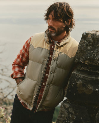 fit model leaning against a wall wearing The Down Vest in Khaki Waxed Ripstop