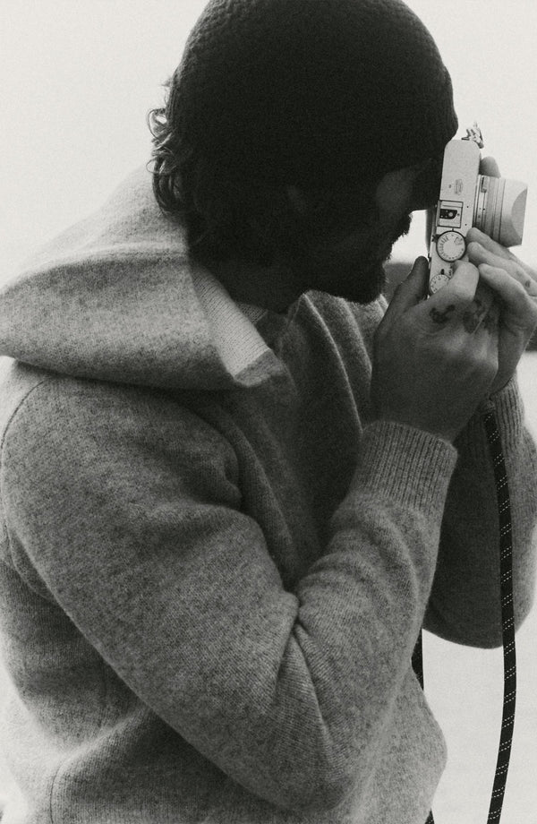 fit model with a camera wearing The Haven Sweater Hoodie in Heather Grey Wool