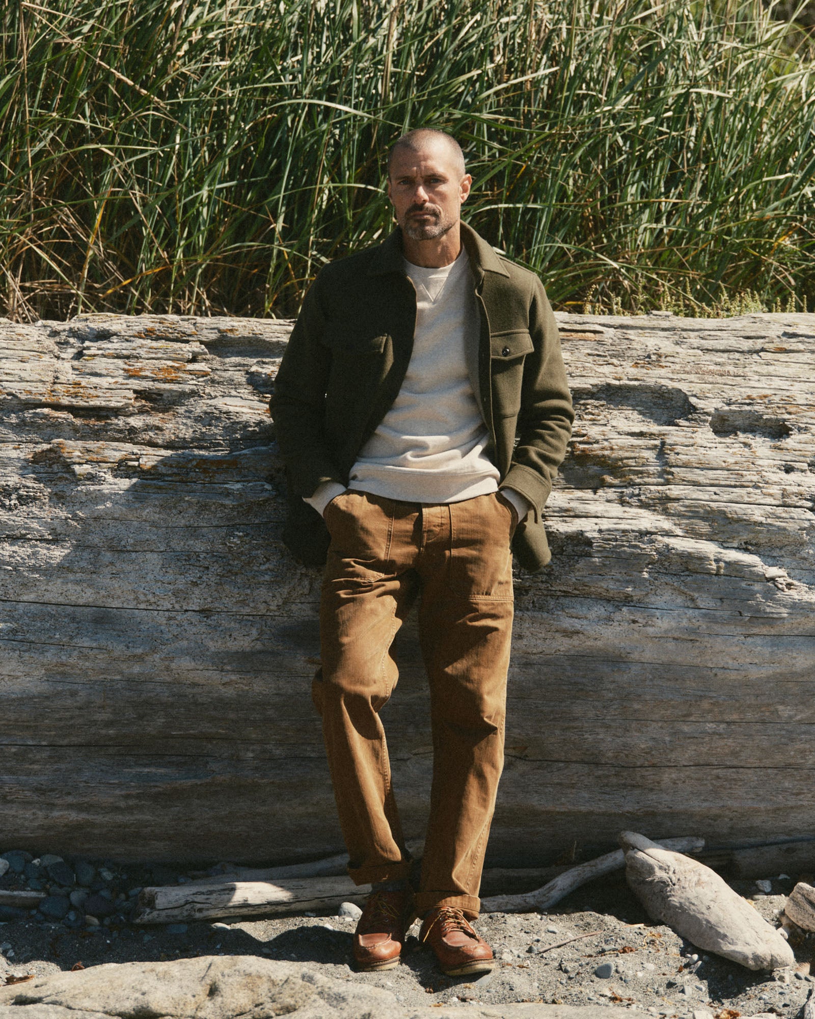 fit model leaning against the wall wearing The Maritime Shirt Jacket in Heather Olive Wool, Outerwear by Taylor Stitch
