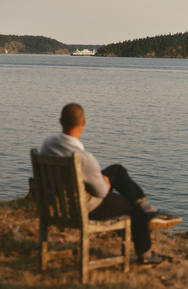 fit model sitting in a chair wearing The Rugby Sweater in Heather Grey Merino