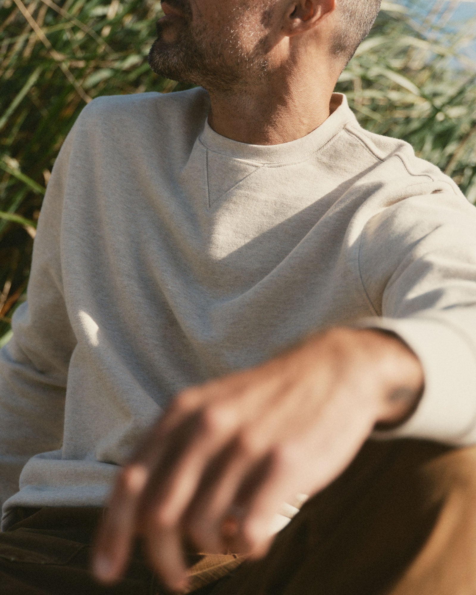 fit model sitting wearing The Sunset Crew in Heather Oat Terry, Knits by Taylor Stitch