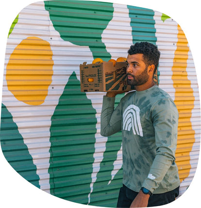 Volunteer walking in front of a bright mural at The Ecology Center wearing The Organic Cotton Long Sleeve Tee in Ecology Center