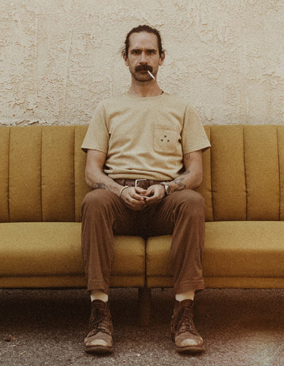 Daren Magee wearing The Heavy Bag Tee in Khaki Dahlia on a vintage couch