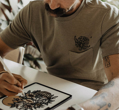 Daren Magee sketching on his tablet in The Heavy Bag Tee in Sage Dahlia