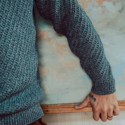 Zach leaning on his easel while wearing The Adirondack Sweater in Blue Melange.