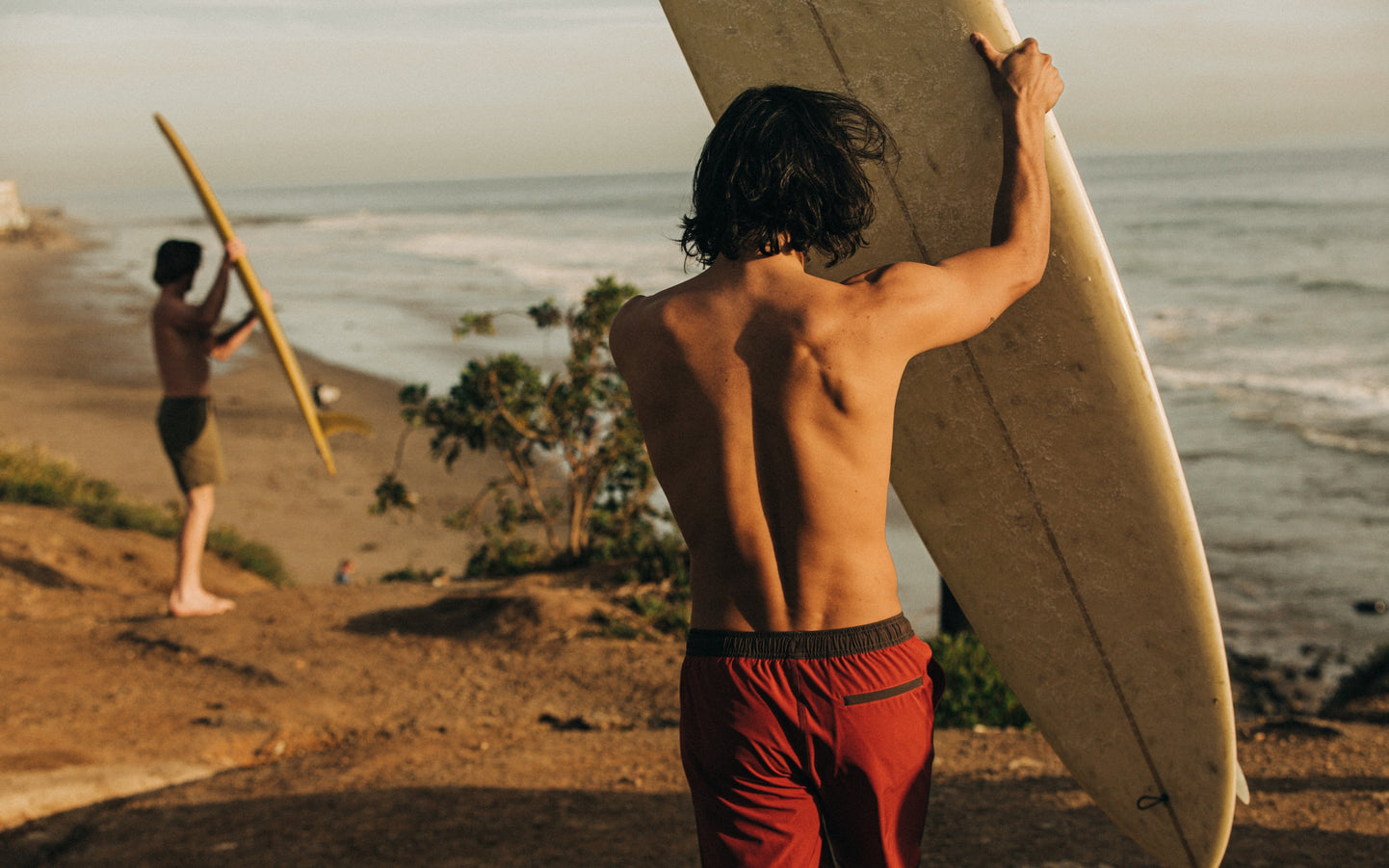 Models holding surfboards by the sea