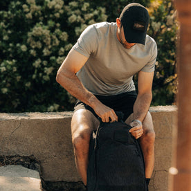 fit model zipping up backpack wearing The Merino Base Layer Tee in Sharkskin 