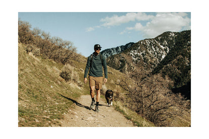 Alex hiking a trail through snow-dusted mountains with his dog beside him.