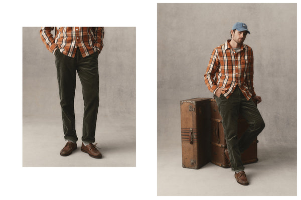 fit model leaning against the wall wearing The Carnegie Pant in Olive Corduroy