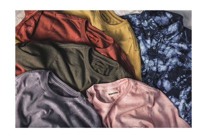 Several dyed tees and a button down, laid flat.