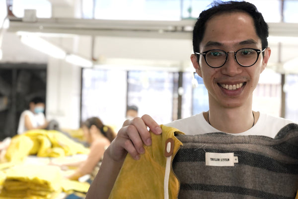 A factory worker holding up a Taylor Stitch jacket.