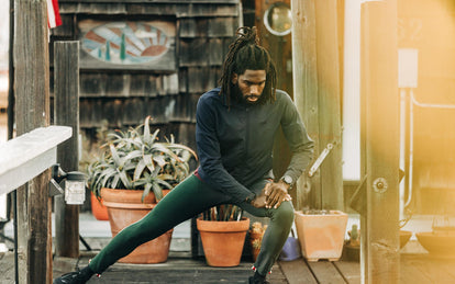 Our guy stretching on a wooden deck with pot plants in the background.