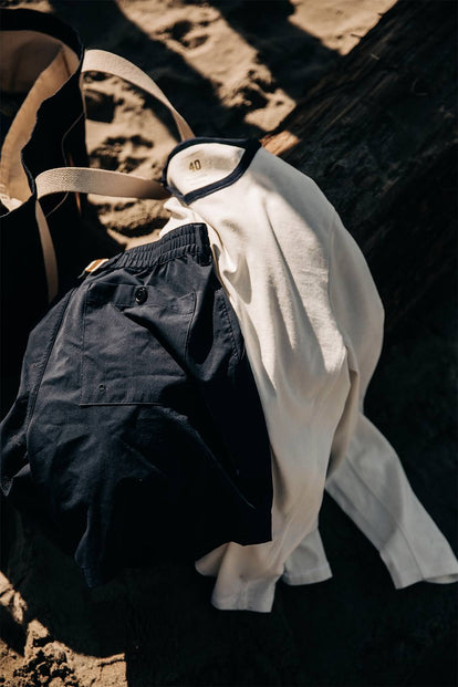 Shorts and a shirt laid over a bag on the beach.