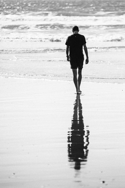 Black and white long shot of our guy walking into the ocean.