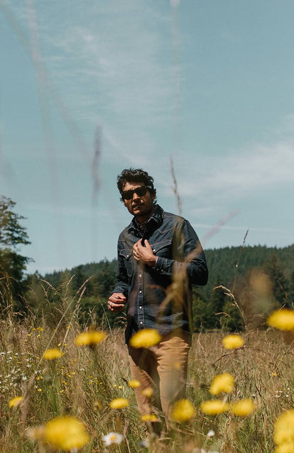Man wearing a selvage western shirt in a field of wildflowers.