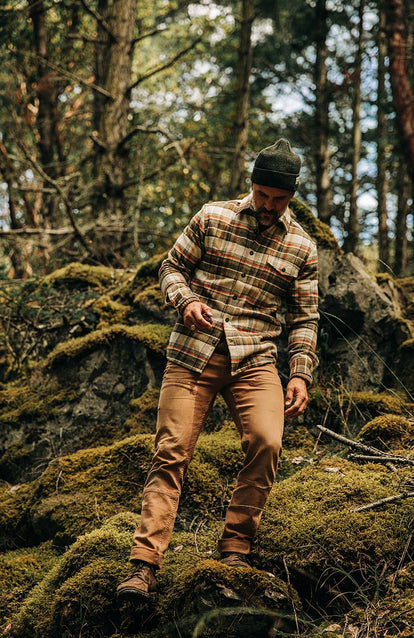 A man wearing the Tan Plaid Crater Shirt traversing through the PNW forests.