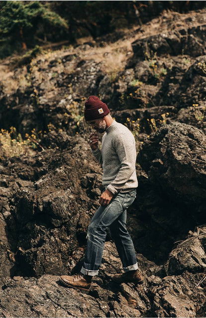 A man traversing over rocks near the water.