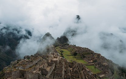 Aerial shot of mountaintop ruins, enveloped in light cloud.