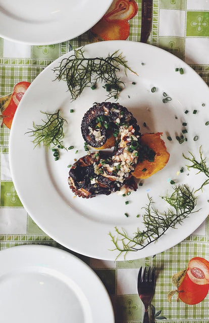 A tastefully presented plated grilled octopus tentacle.