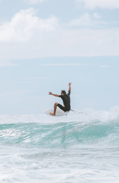 Surfer catching some air on a foamy wave.