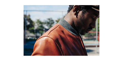 Close up side-view shot of a man's shoulders, showing the collar on a brown leather jacket.