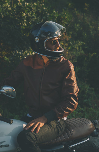 A black-helmeted man with his visor open, looking back over his shoulder.