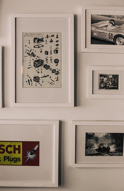 Various framed automotive-related art, framed and hung on a wall.