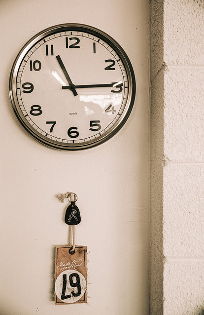 A wall clock with keys hanging underneath.