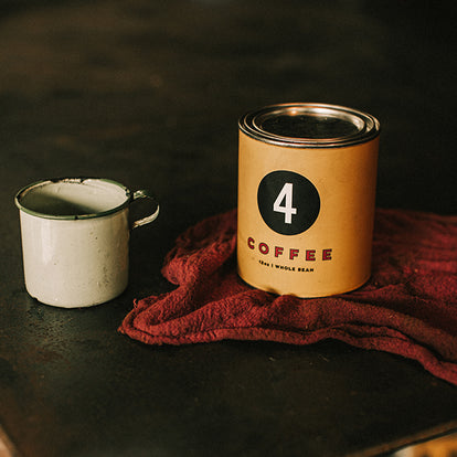 A FourTillFour coffee can and camp mug, on a shop rag.