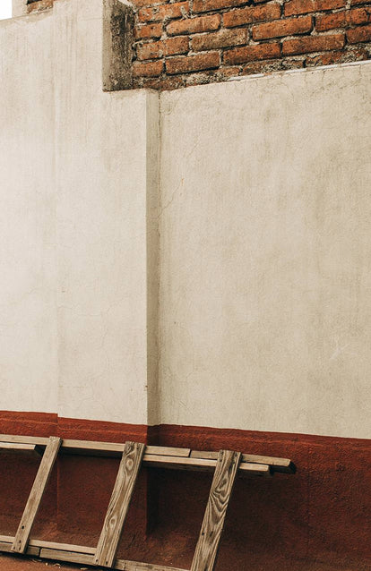 shot of a white and red wall with a ladder on the ground
