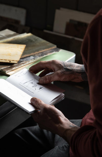 Tim journaling, wearing the crewneck in brick red terry.