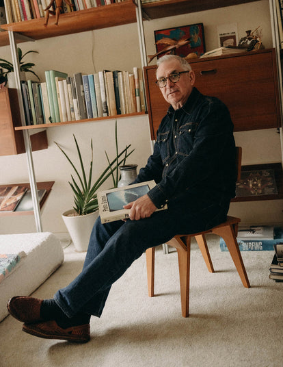 Jeff Farnsworth sitting on a stool with one of his books