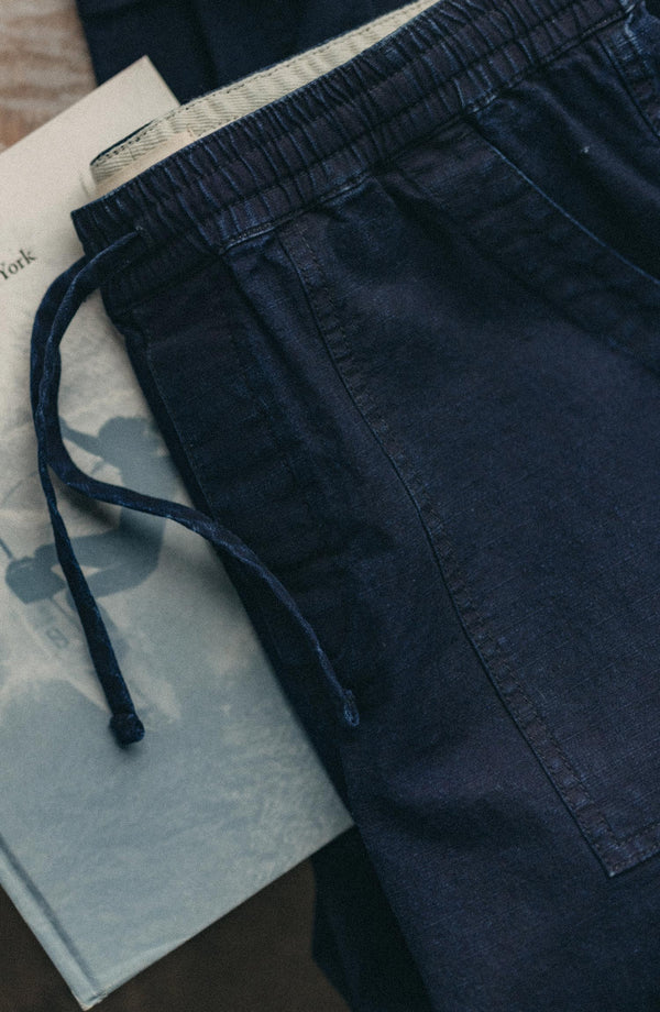editorial flatlay of The Breakwater Pant in Rinsed Indigo Ripstop