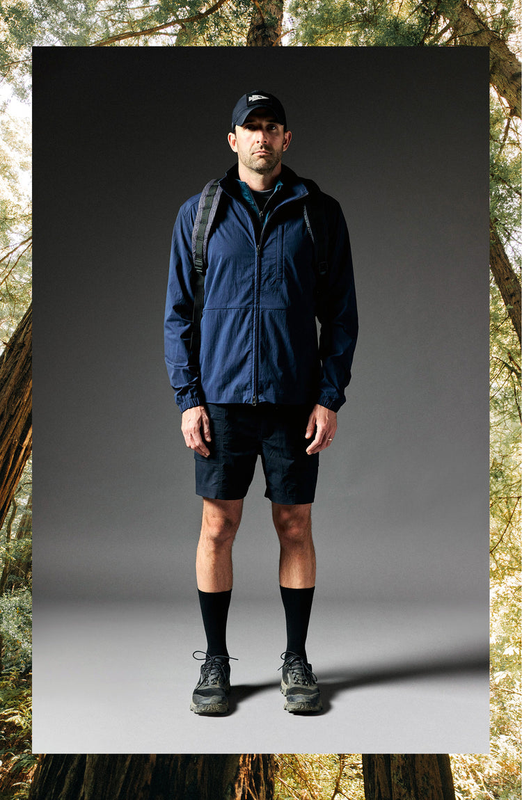 fit model standing wearing The Deploy Packable Shell in Dark Navy